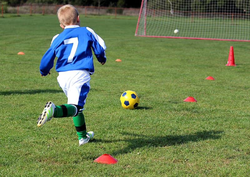 man-in-blue-and-white-jersey-shirt-playing-soccer-on-green-grass-field-during-daytime